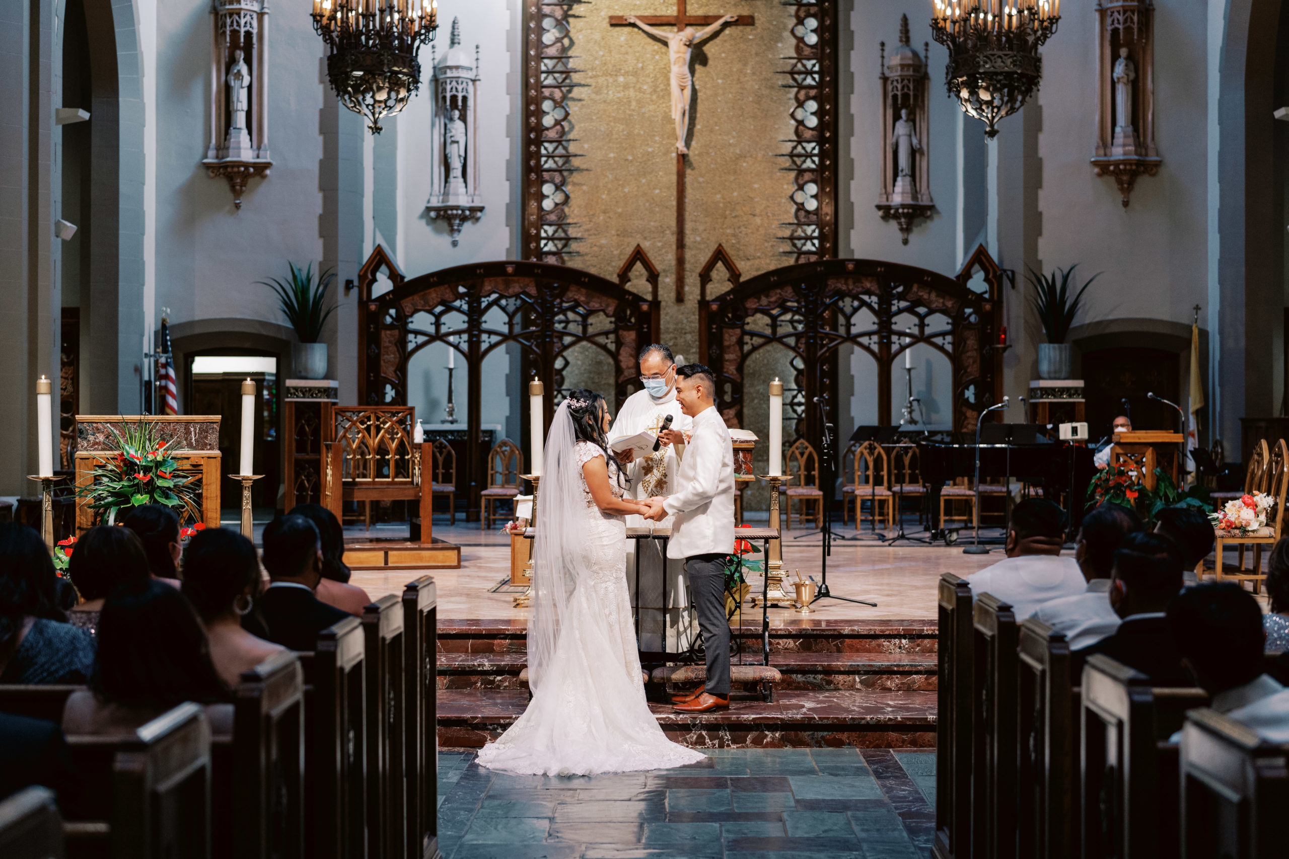 bride and groom stand at altar holding hands during Catholic Church wedding ceremony