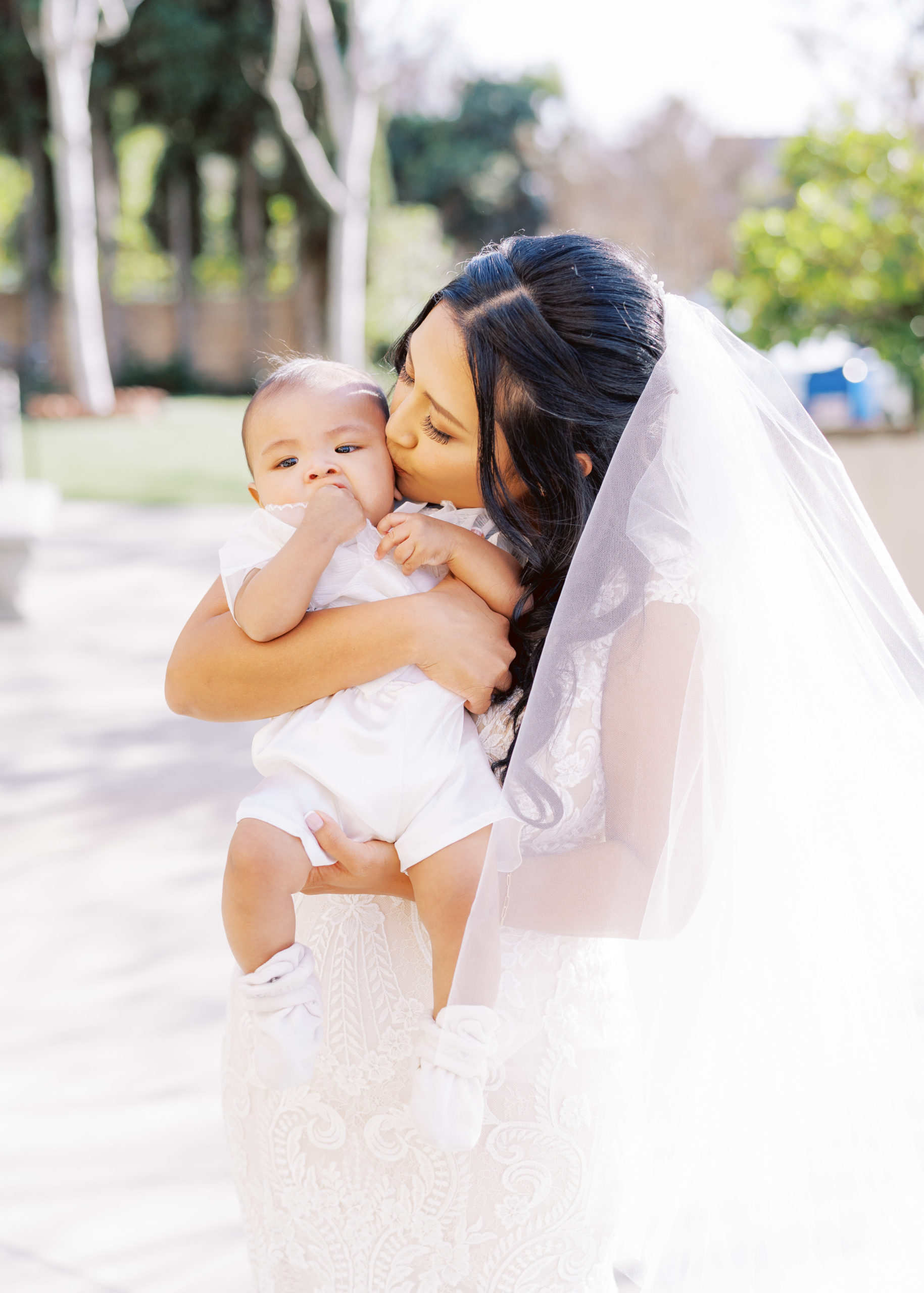 bride kisses baby during wedding portrait shots