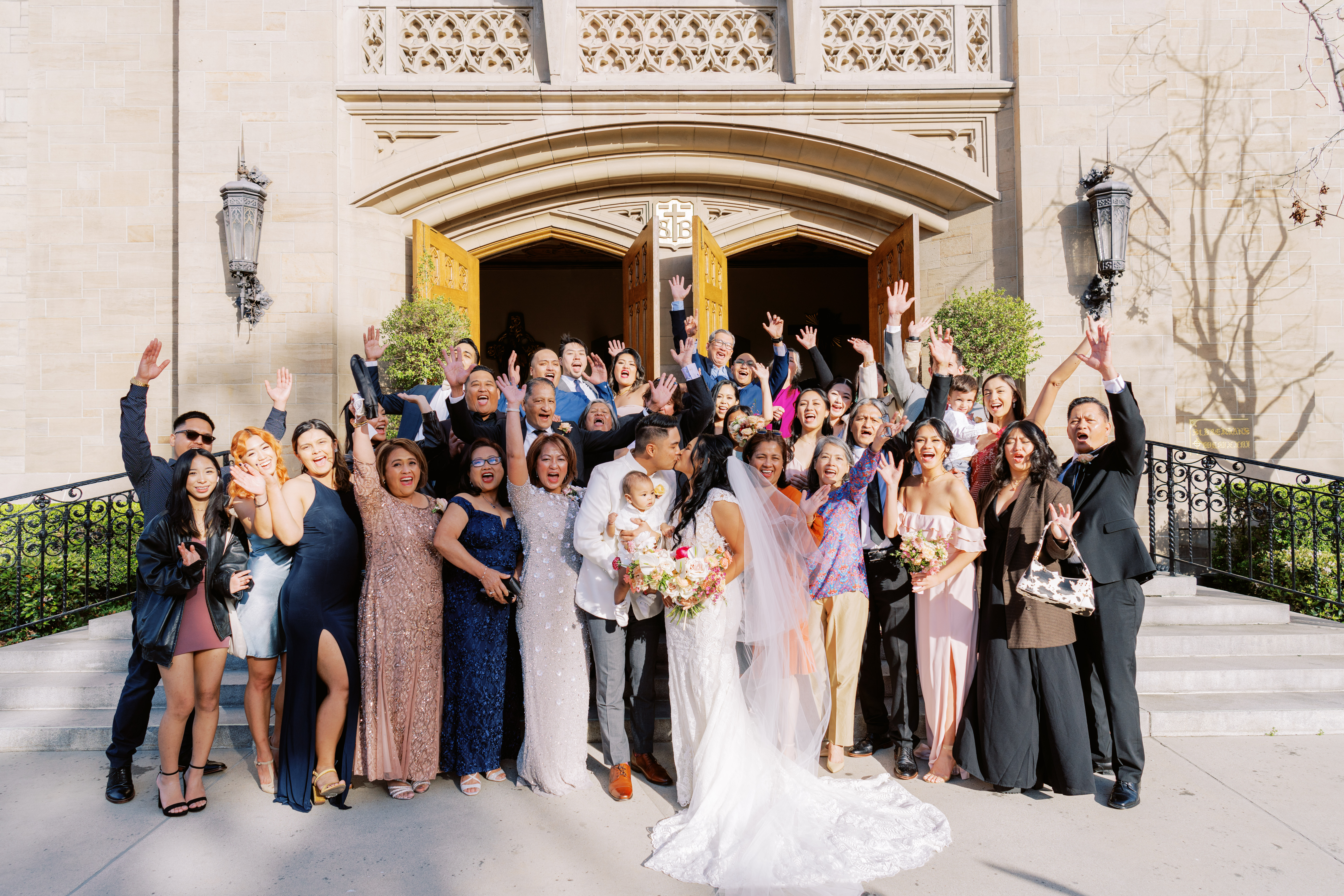 bride and groom kiss outside of church with all their guests in the background
