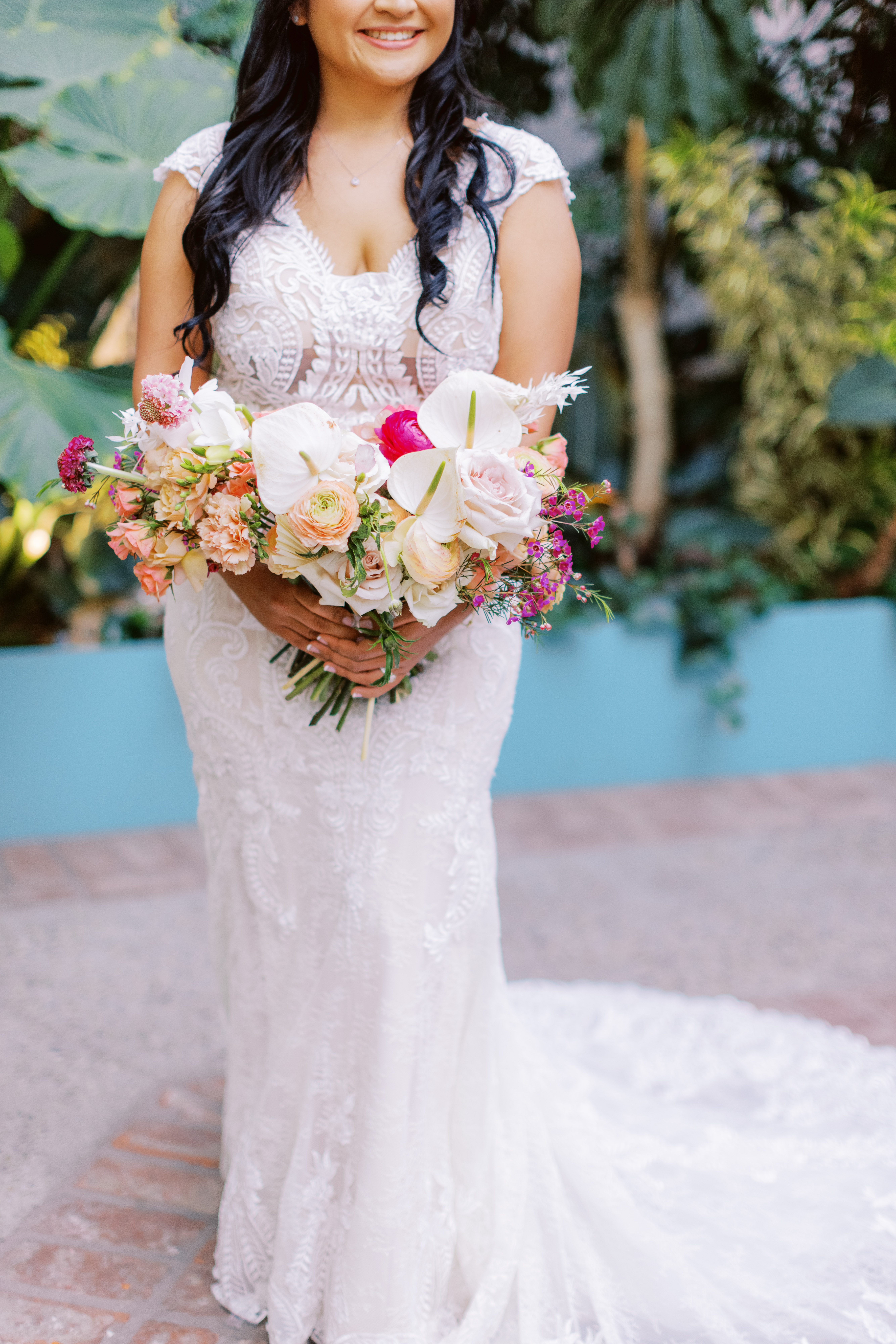 bride in lace dress with bright tropical bouquet poses during cocktail hour at The Valentine DTLA 