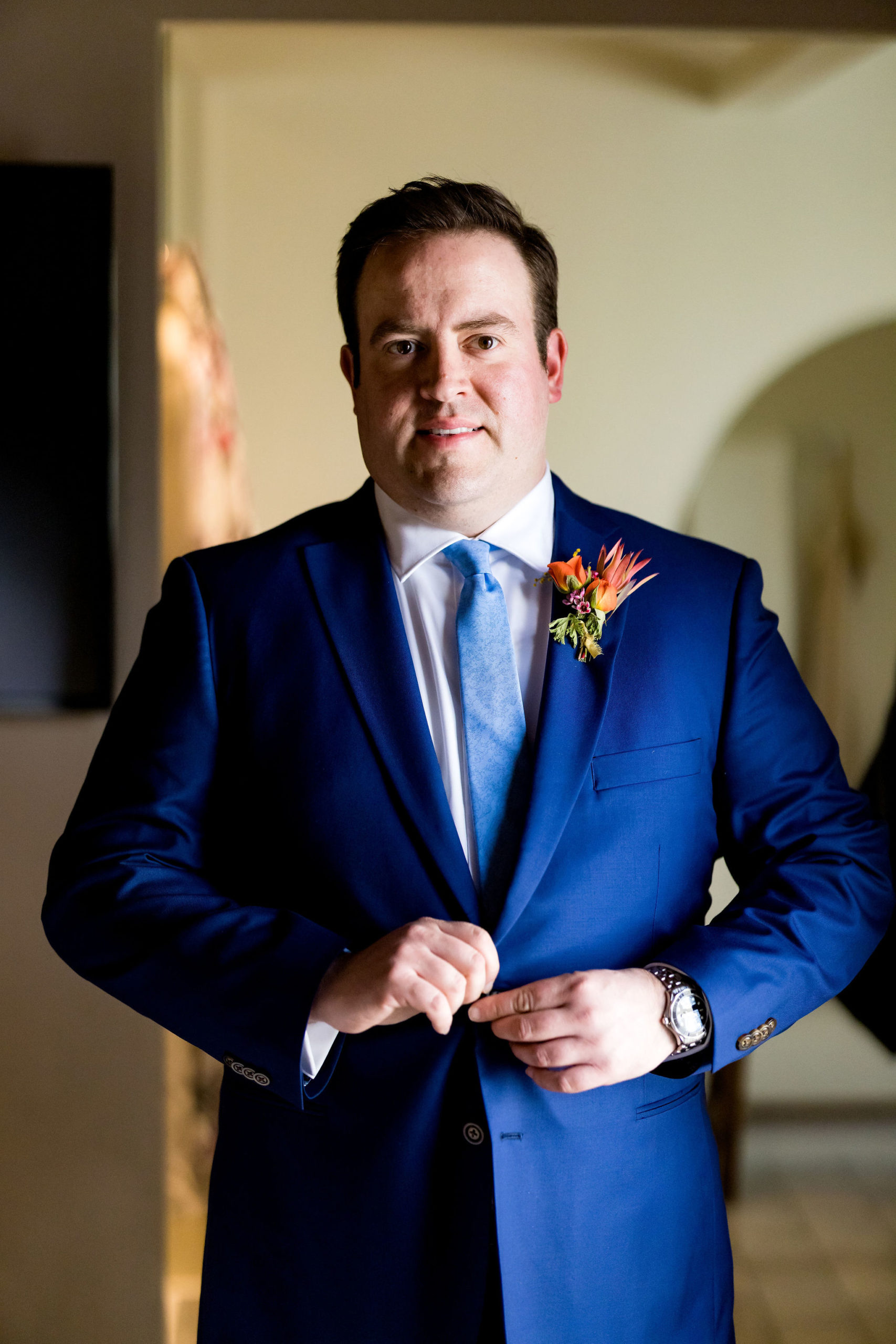 groom in bright blue suit with blue tie and bright floral boutonniere 