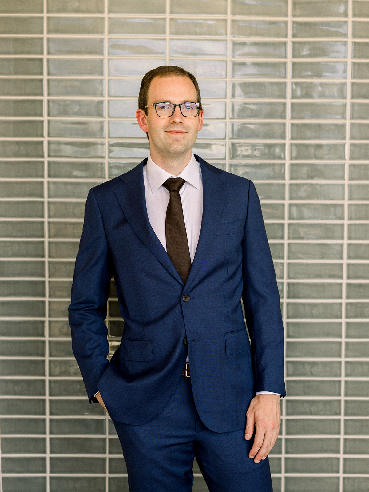 groom wearing glasses with navy suit and black tie