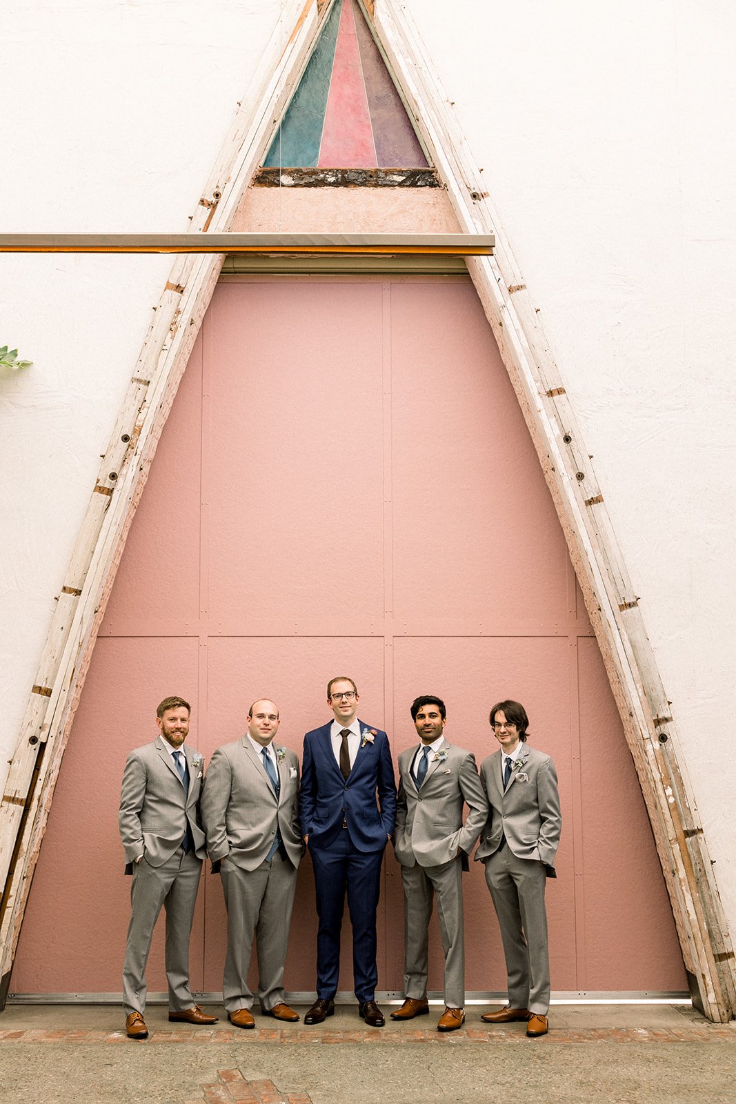 groom in navy suit and black tie stands with groomsmen in grey suits and blue ties at The Grassroom DTLA