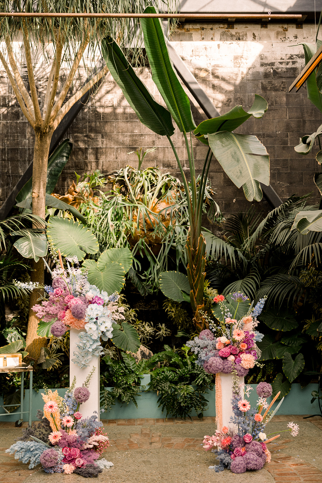 contemporary wedding ceremony with pillars covered in wild pastel floral arrangements at The Grass Room DTLA