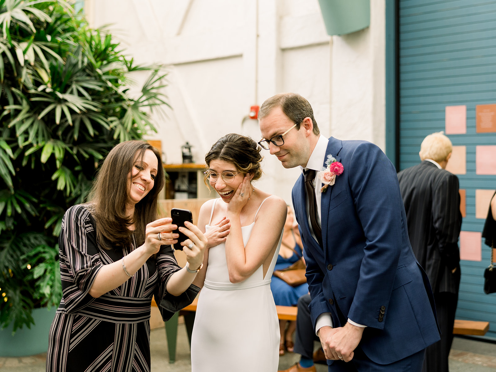 bride and groom wearing glasses look at picture on phone