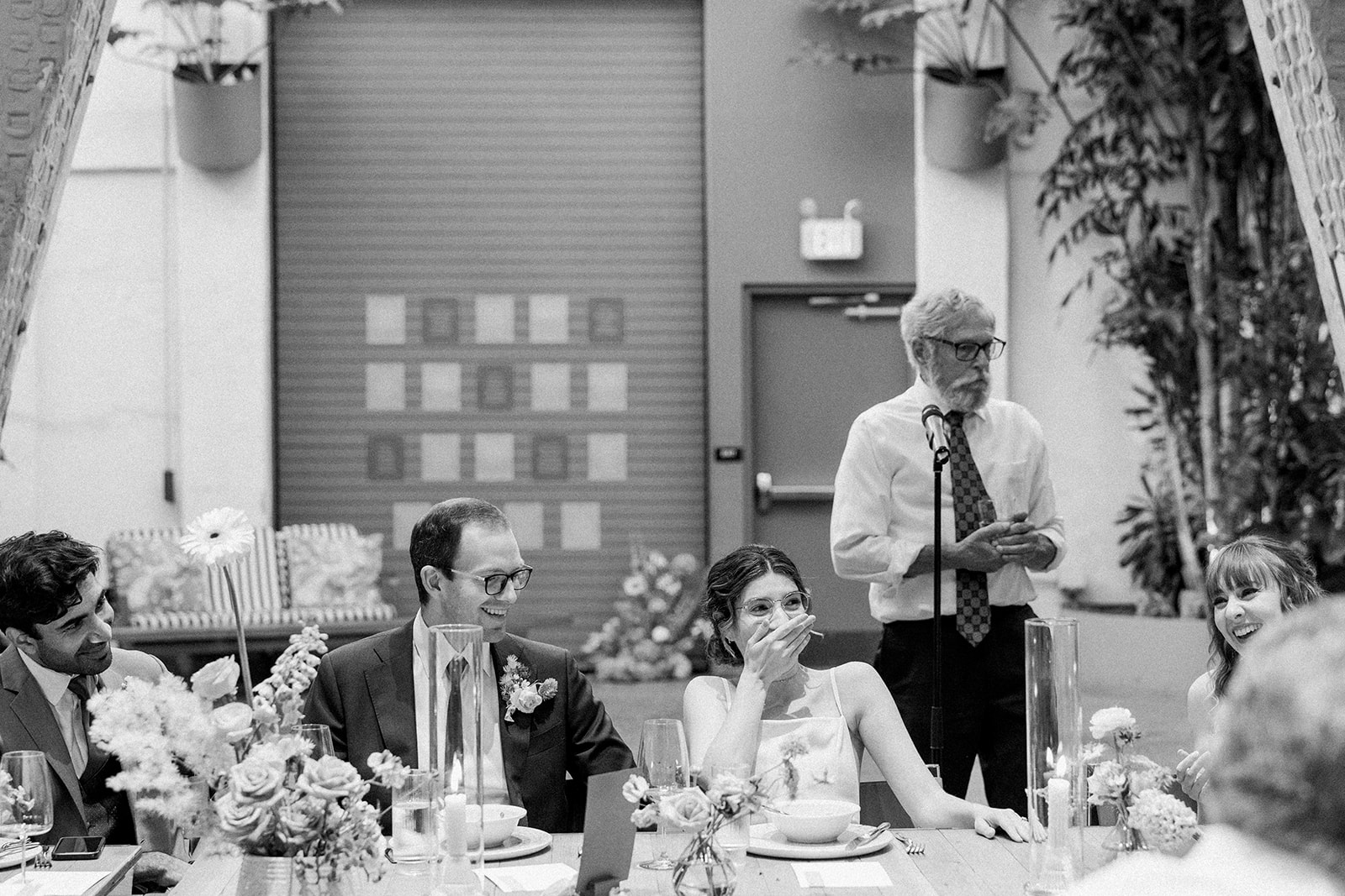 black and white photo of bride and groom laughing during wedding reception 