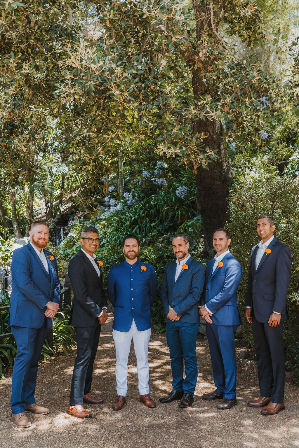 groom in cobalt blue suit stands groomsmen in blue and grey suits at Lake Shrine Temple