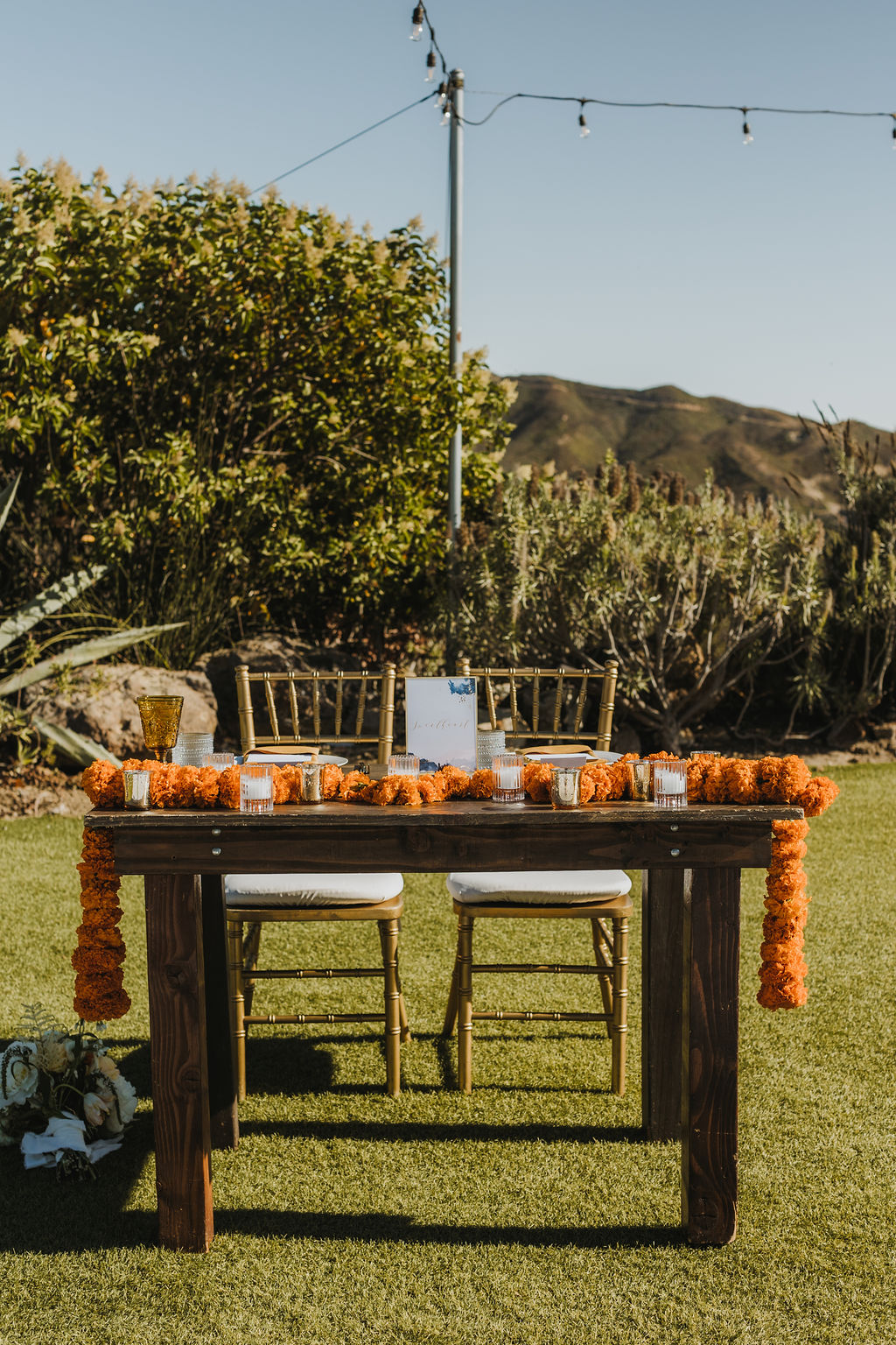 sweetheart table for wedding reception at Saddlerock Ranch with orange marigold floral arrangements