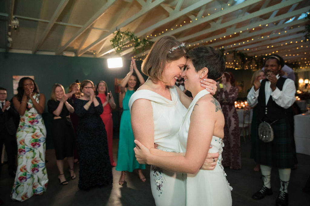 two brides embracing one another during wedding reception 