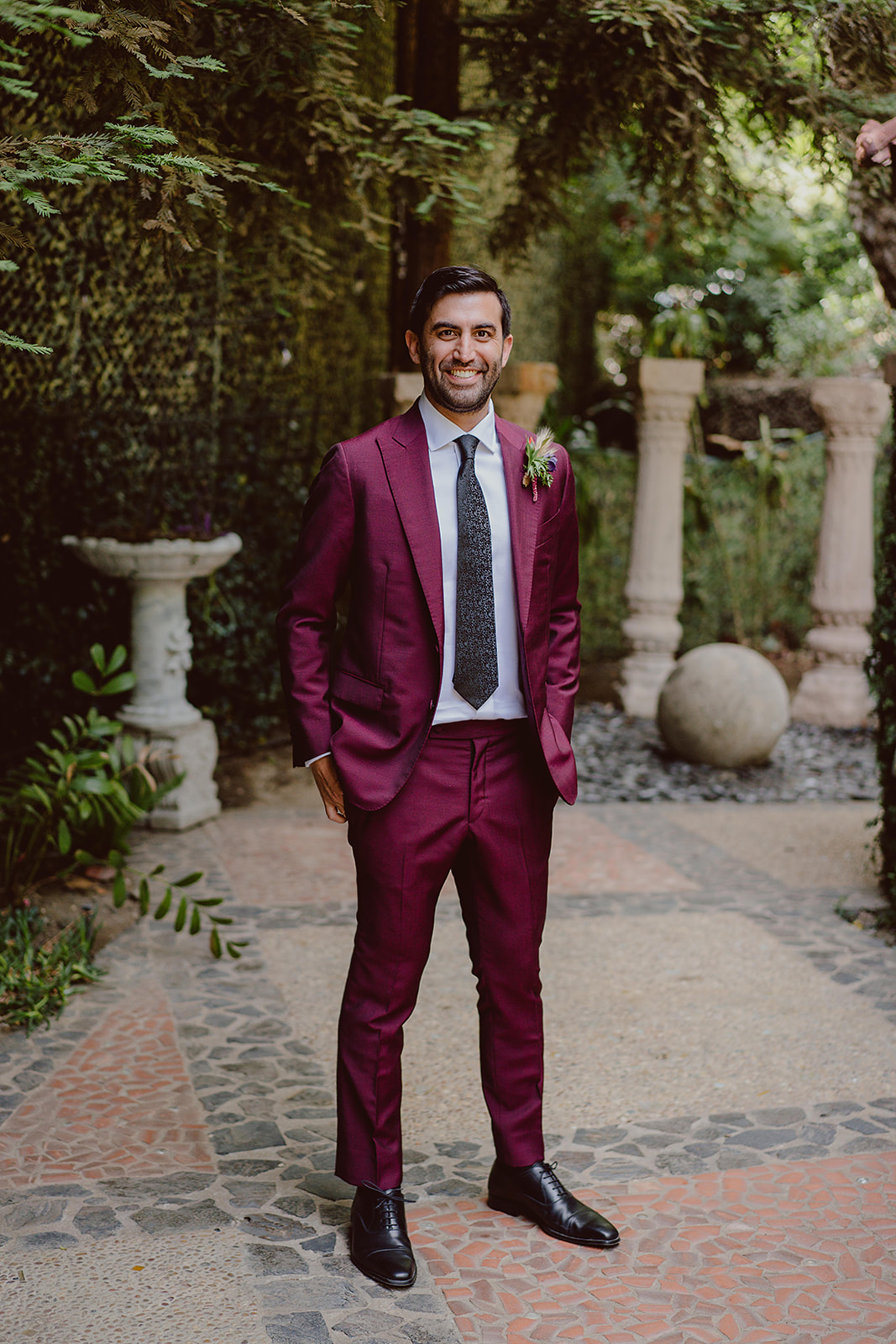 groom in burgundy suit with black textured tie  