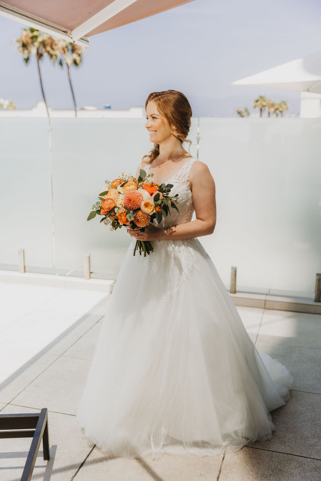 red haired bride in vneck embellished tulle ball gown holds bright orange bridal bouquet