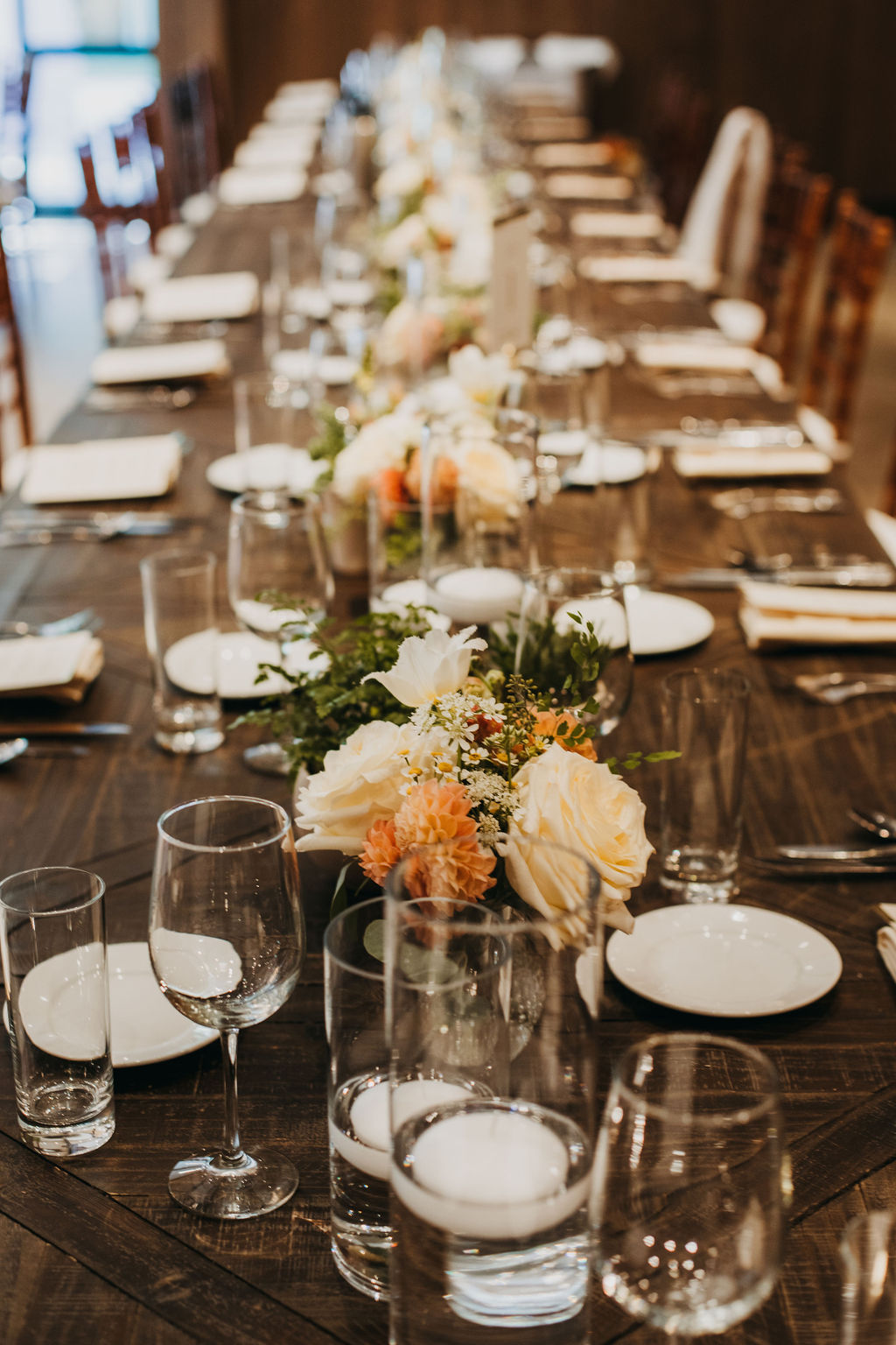 wedding reception at Calamigos Ranch with wooden chairs and orange and pink floral table arrangements