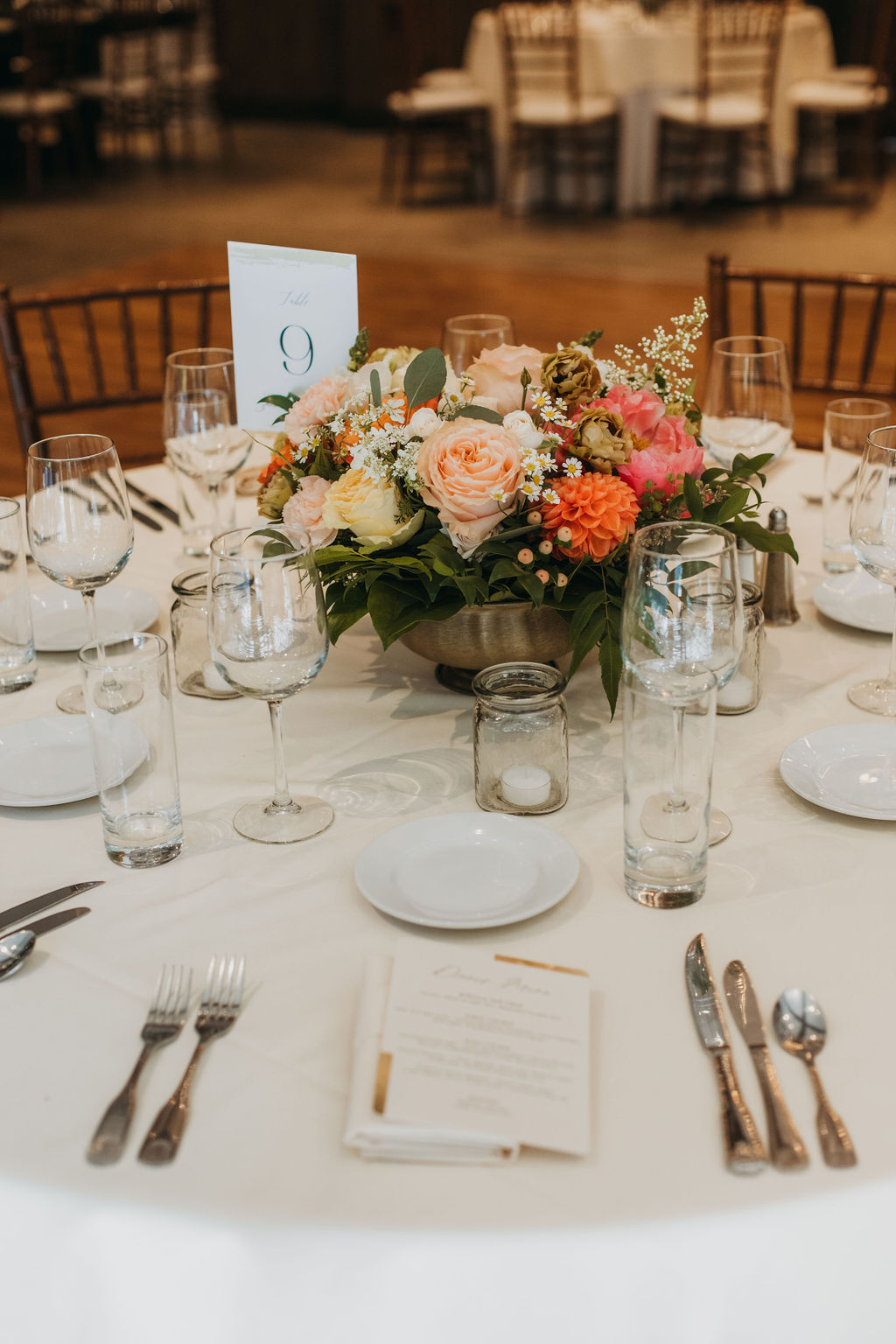 wedding reception at Calamigos Ranch with wooden chairs and orange and pink floral table arrangements
