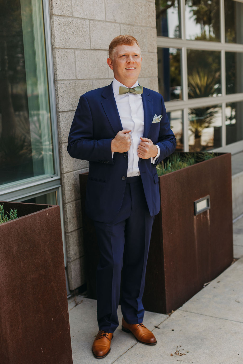 groom in navy blue suit with green bowtie 