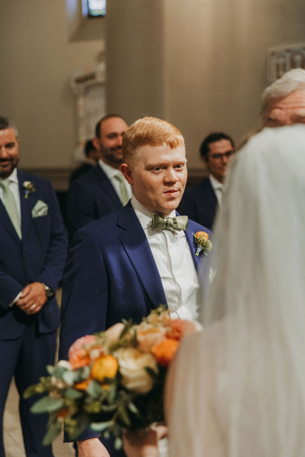 emotional groom in navy suit looking at bride 