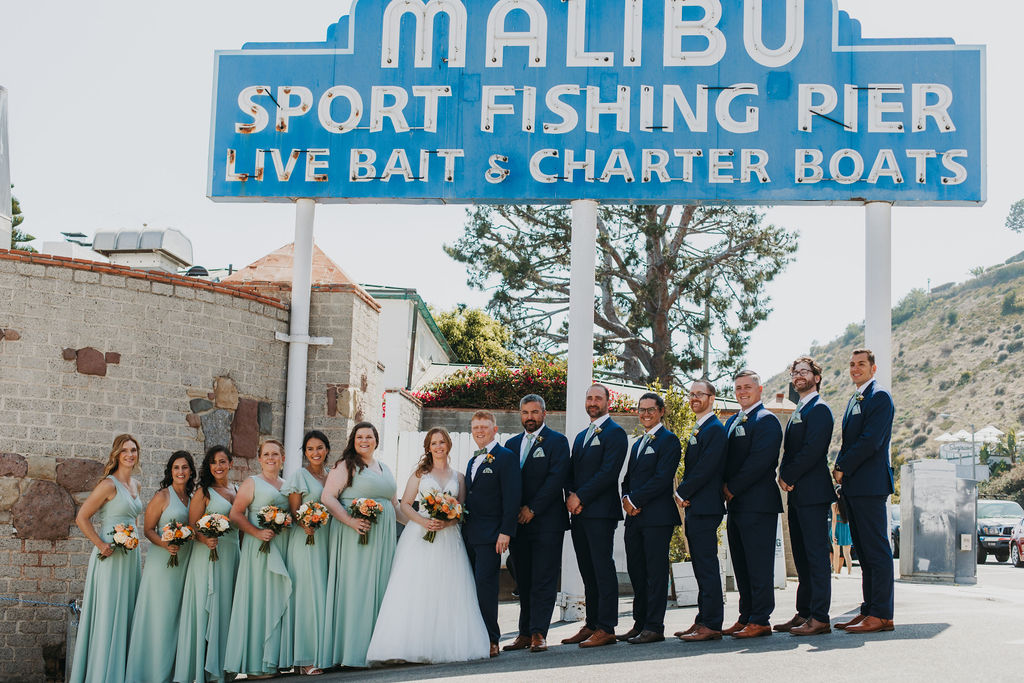 bride and groom with wedding party in mint green dresses and navy blue suits taking photos in Malibu