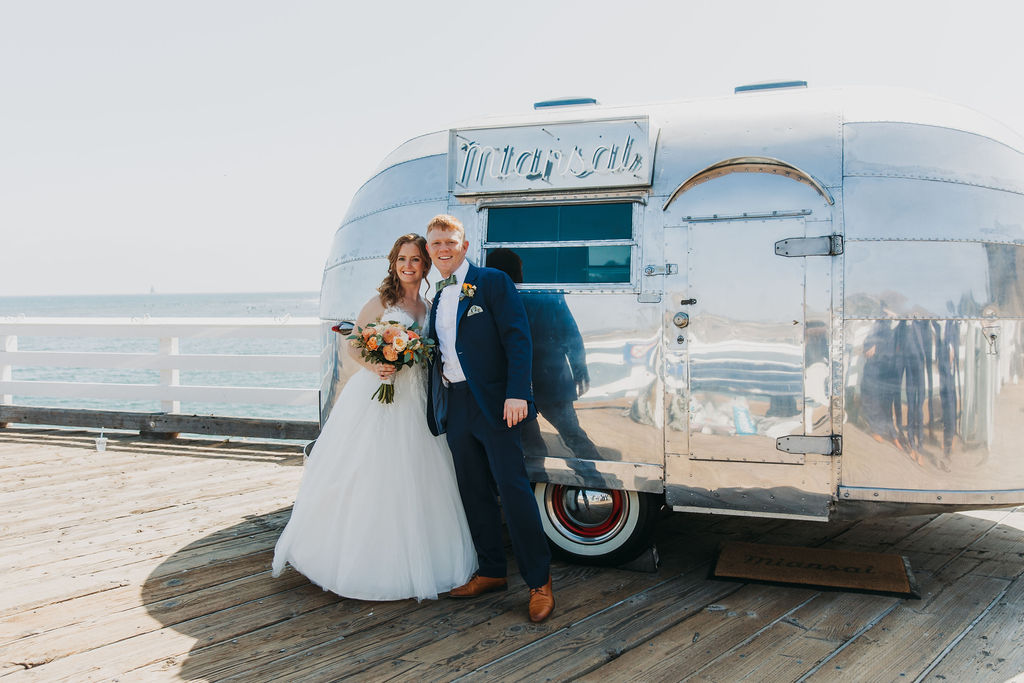 bride in v-neck tulle ballgown with groom in navy blue suit on pier in Malibu