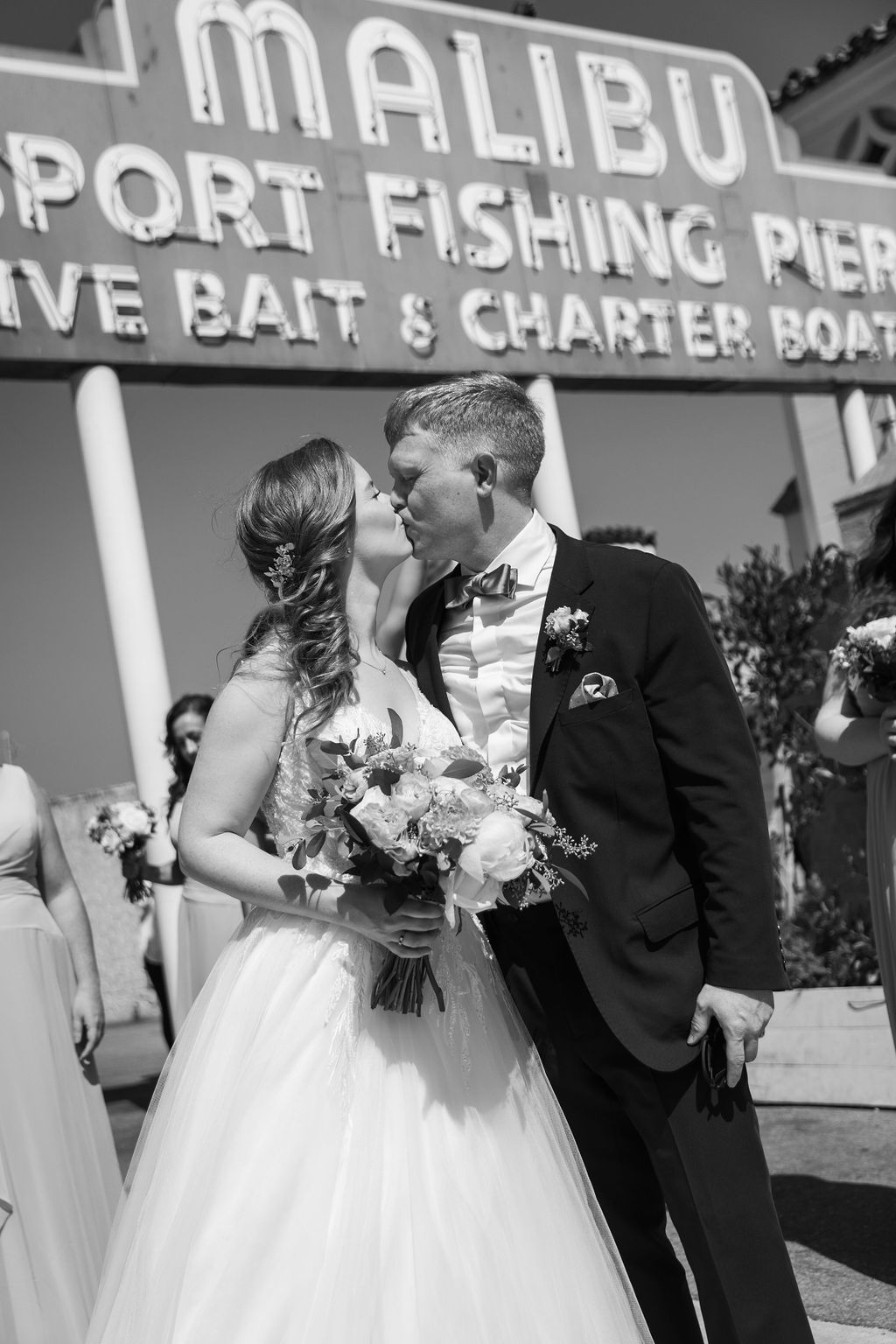 bride in v-neck tulle ballgown with groom in navy blue suit on pier in Malibu
