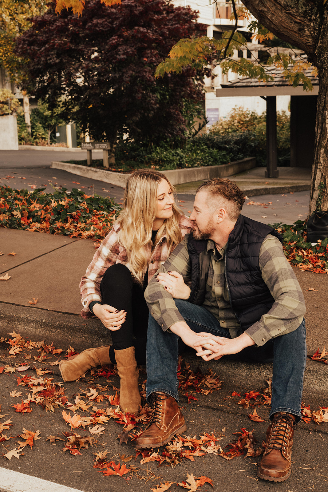 fall engagement photo session with couple sitting on sidewalk 