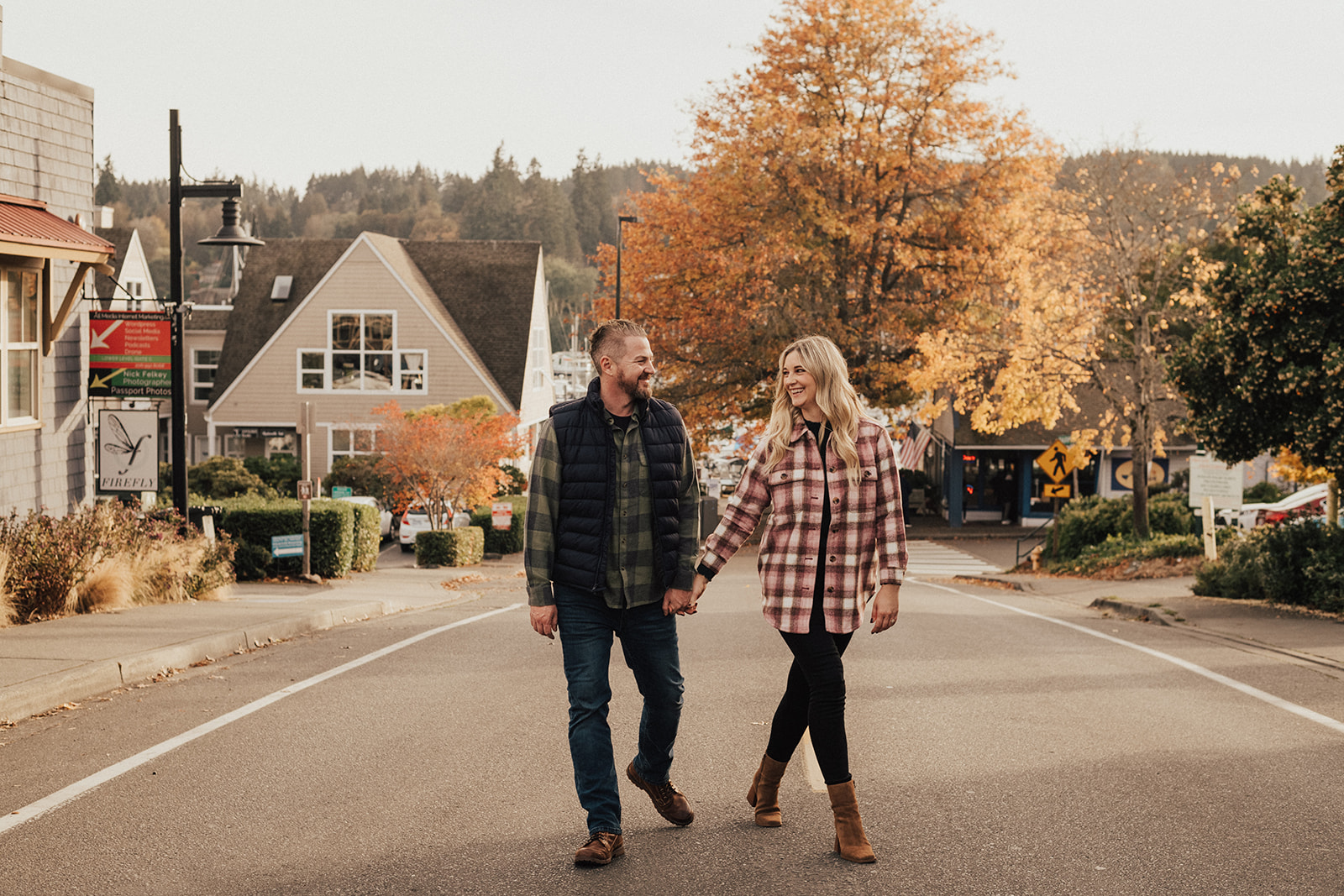 Newly engaged couple in plaid shirts holding hands while walking down the street in Seattle during the fall 