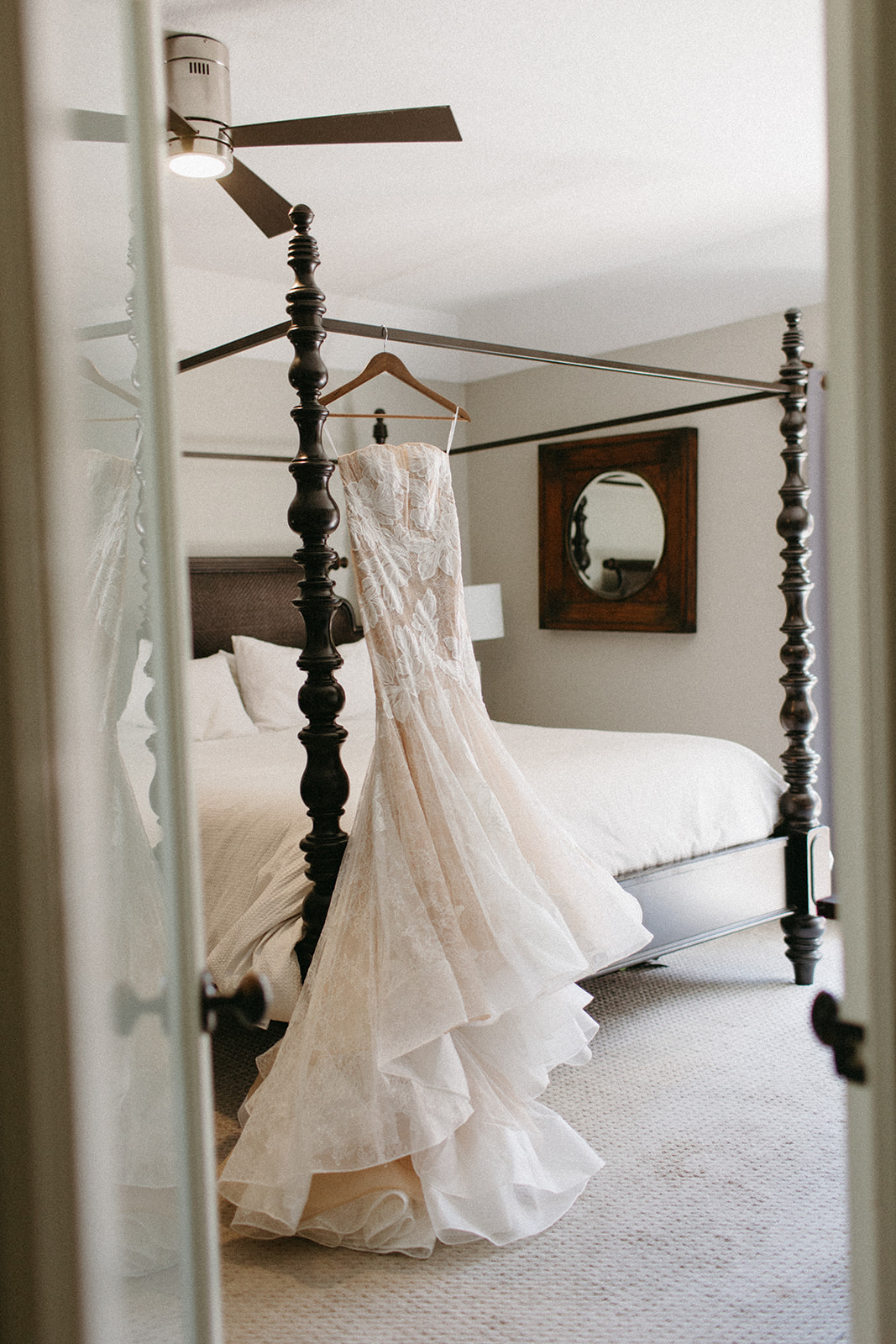 champagne strapless lace wedding dress hanging from hanger in hotel room