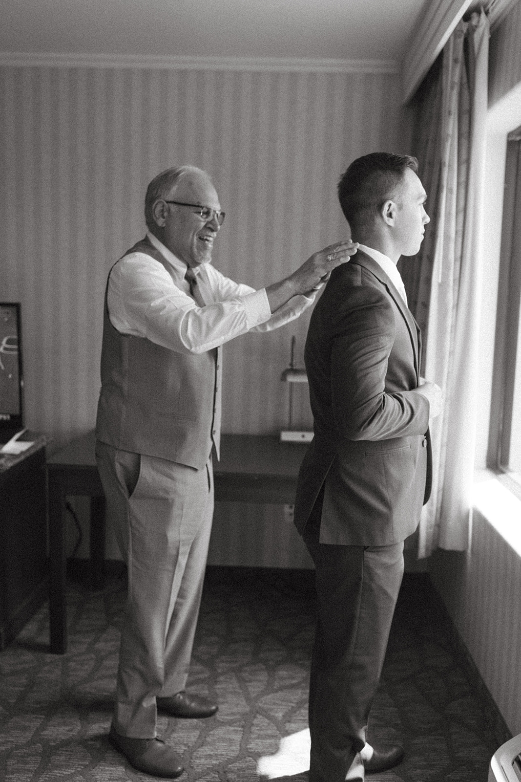 black and white photo of groom and father of the groom getting ready for wedding day