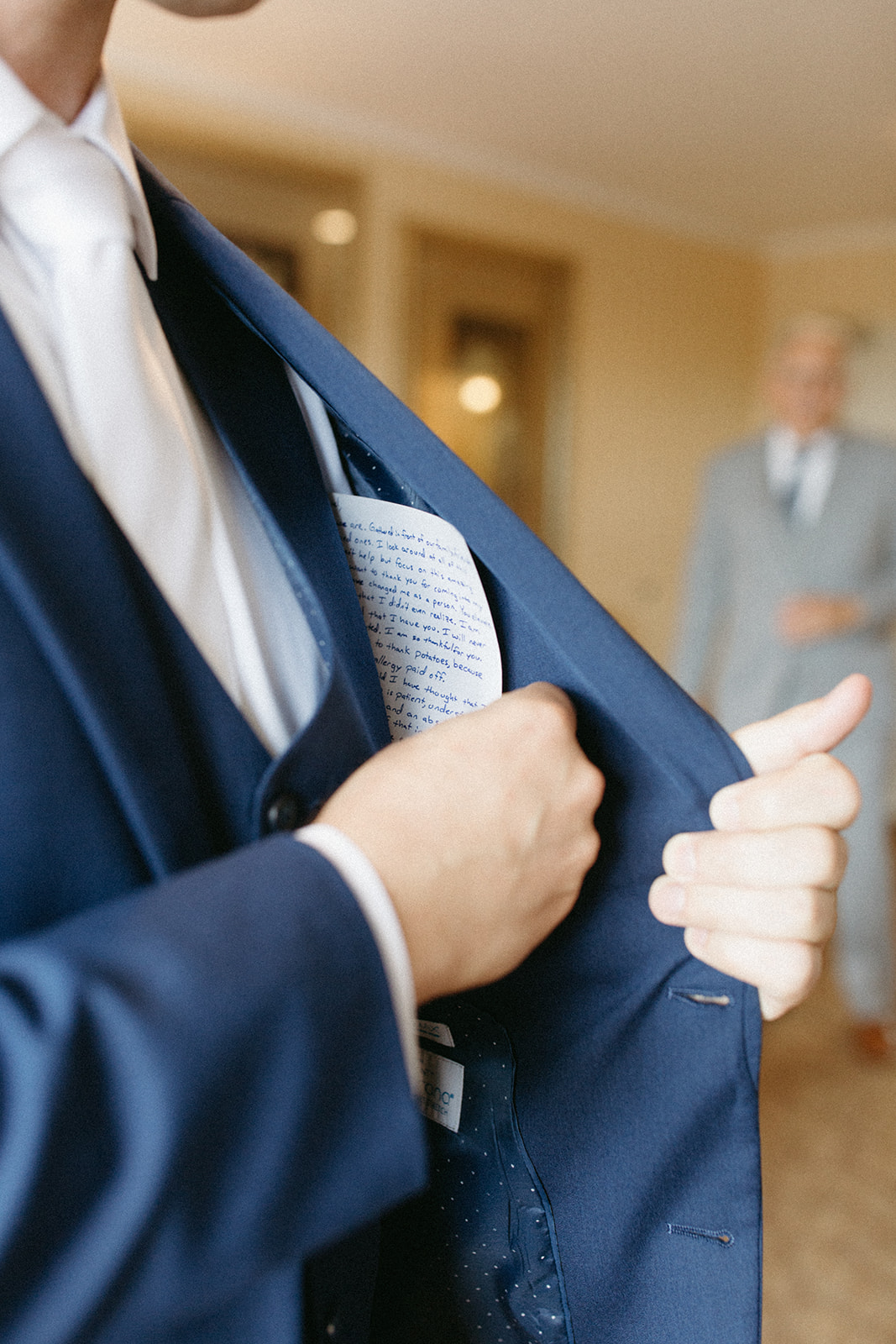 groom tucking hand written vows into suit coat pocket