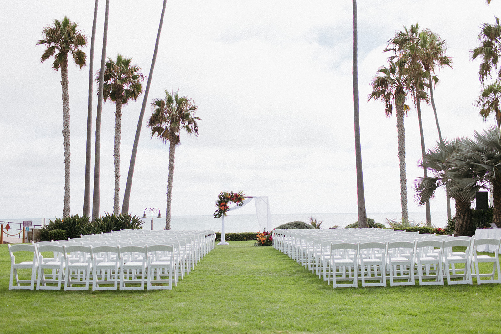 outdoor tropical wedding ceremony at Ole Hanson Beach Club with ocean view and white chairs