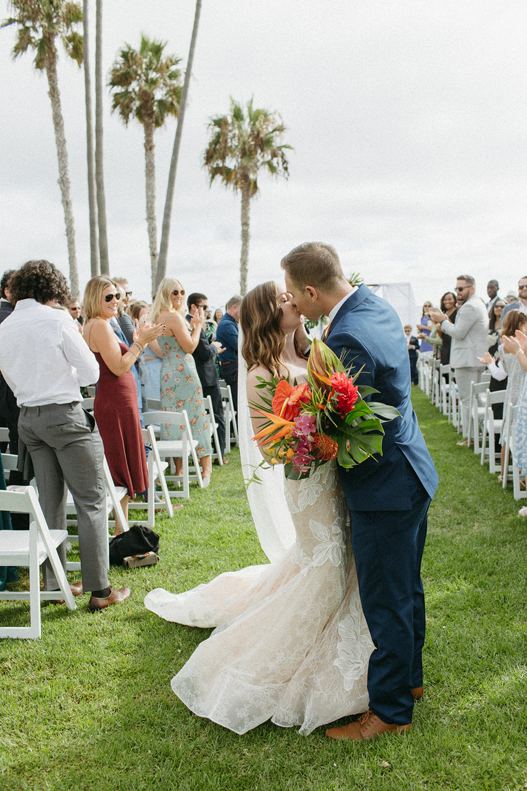 bride and groom kiss at the end of the aisle during recessional of their tropical wedding ceremony at Ole Hanson Beach Club