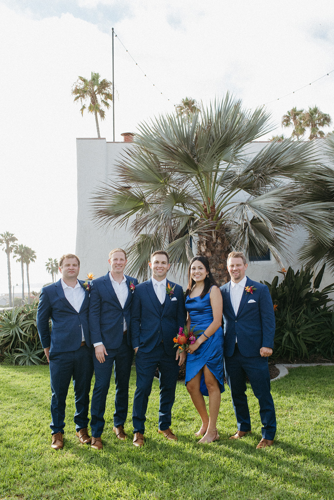 groom with co ed wedding party wearing blue and tropical inspired florals 