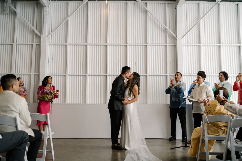bride and groom first kiss during colorful cloud themed wedding at The Revery