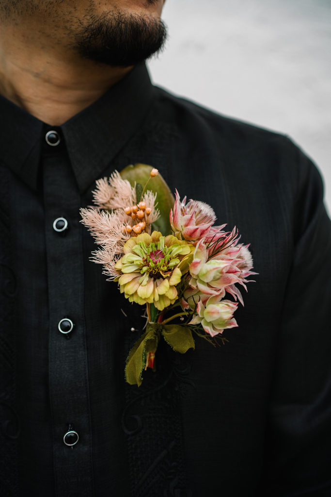 groom in all black suit with bold, modern boutonniere 