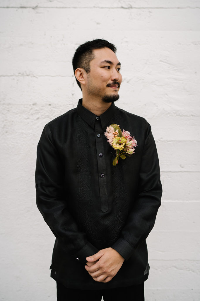 groom in all black suit with bold, modern boutonniere 