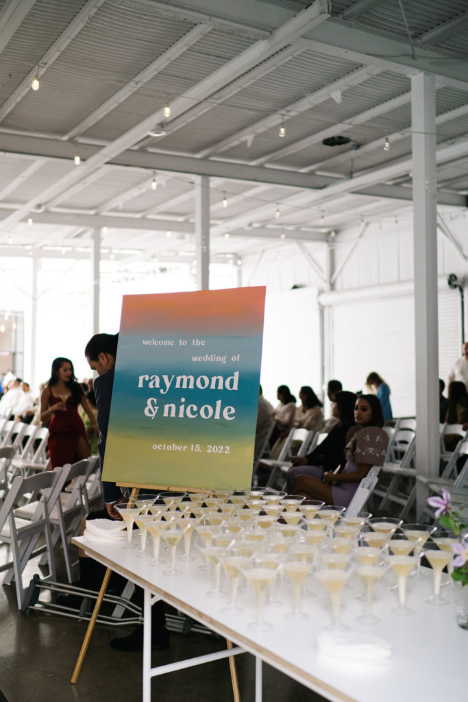 colorful wedding welcome sign next to table of champagne flutes