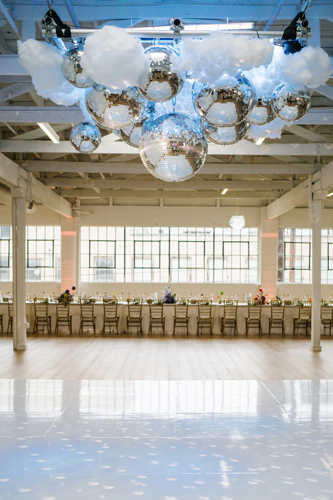 cloud themed wedding reception with disco balls and rainbow inspired floral arrangements at The Revery