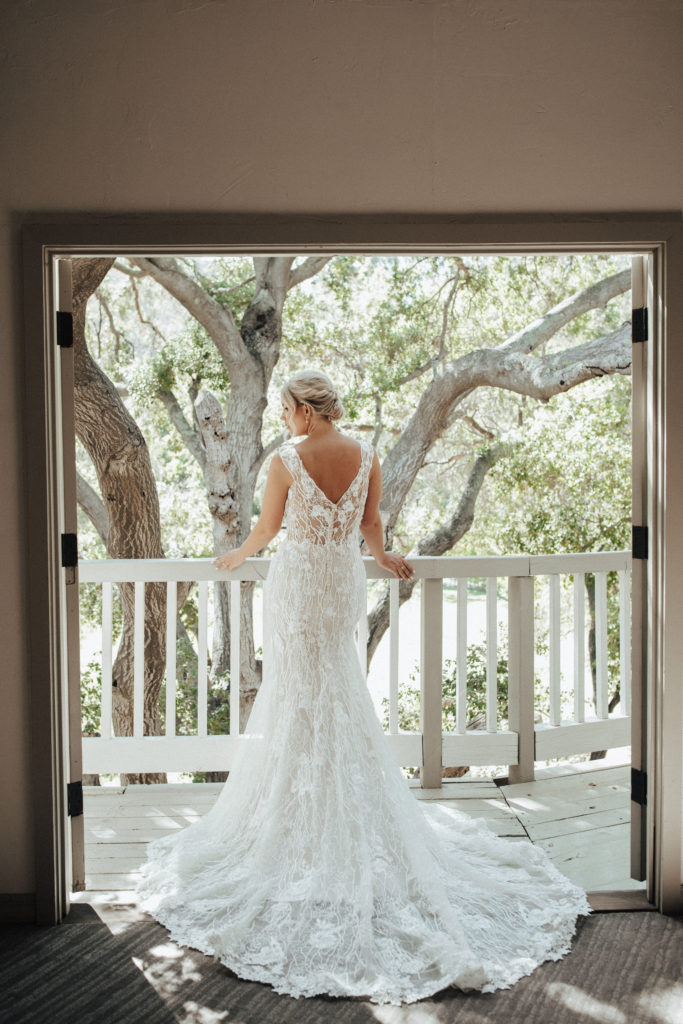 bride in champagne vneck wedding dress with beaded lace overlay standing on balcony of Calamigos Ranch