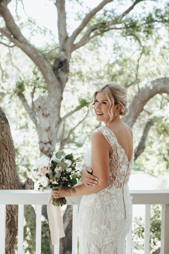 bride in champagne vneck wedding dress with beaded lace overlay standing on balcony of Calamigos Ranch
