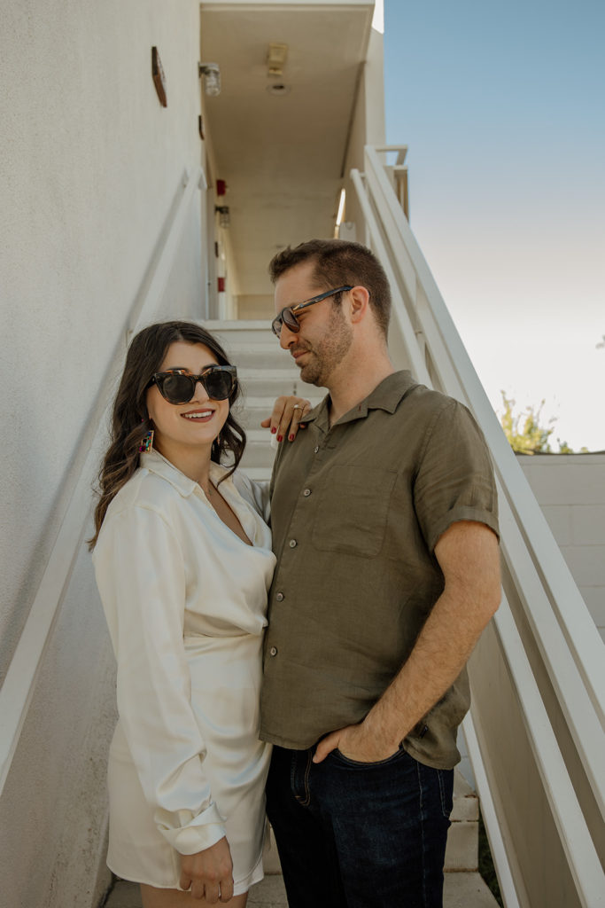 mid-century inspired desert engagement photo session with bride to be in silk mini dress and groom in brown button up on outdoor staircase