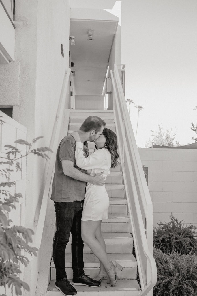 mid-century inspired desert engagement photo session with bride to be in silk mini dress and groom in brown button up on outdoor staircase