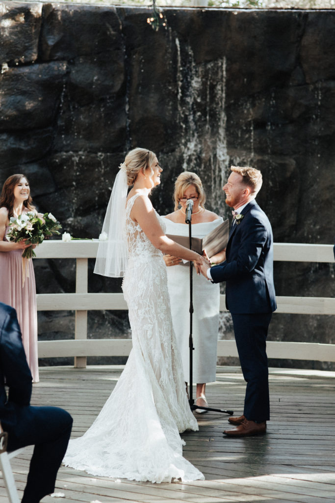 spring wedding ceremony in front of waterfall with soft pink and white flowers at Calamigos Ranch Oak Room