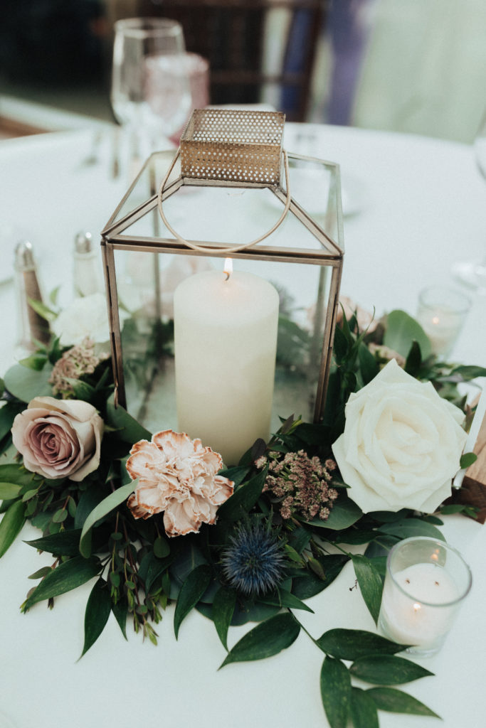 gold framed lantern with candle nestled in soft pink and white florals