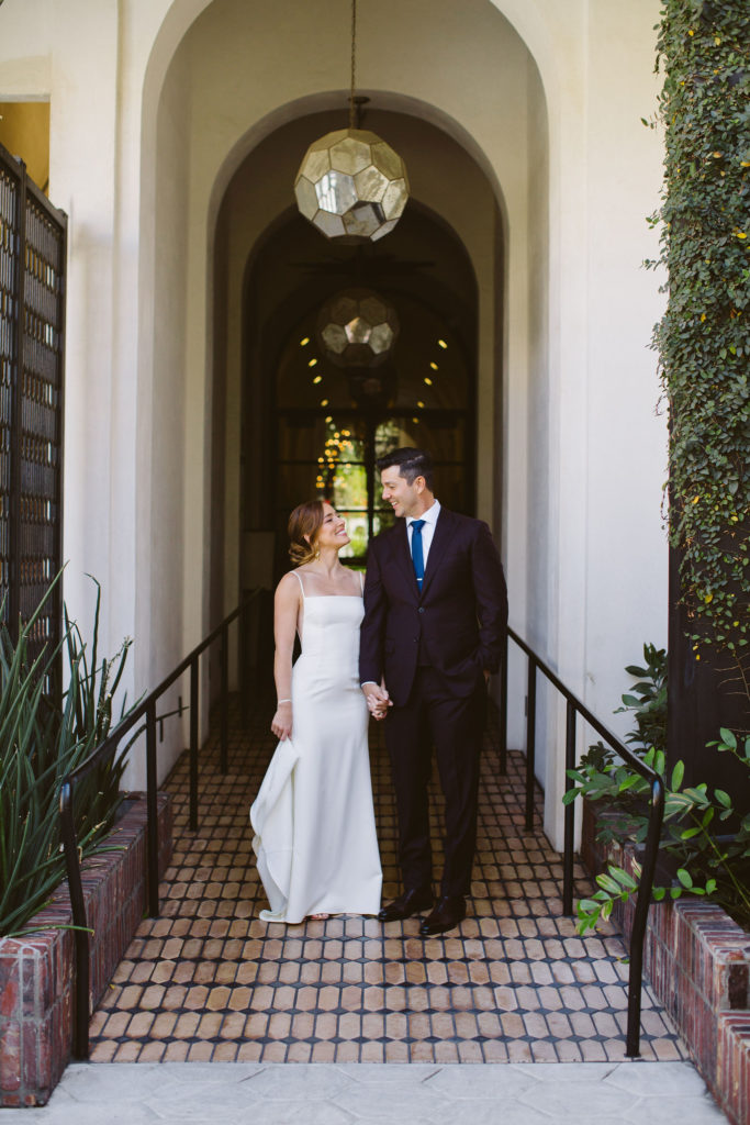 bride in modern square neck spaghetti strap wedding dress and groom in deep plum suit take portrait shots at Hotel Figueroa