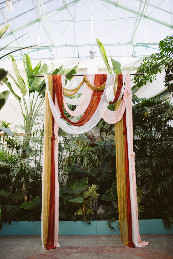 earth toned draping for ceremony arch surrounded by plants at Valentine DTLA