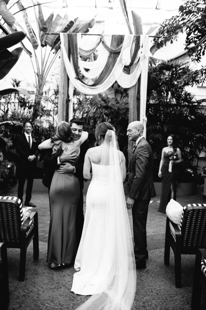 groom hugging brides parents during wedding ceremony