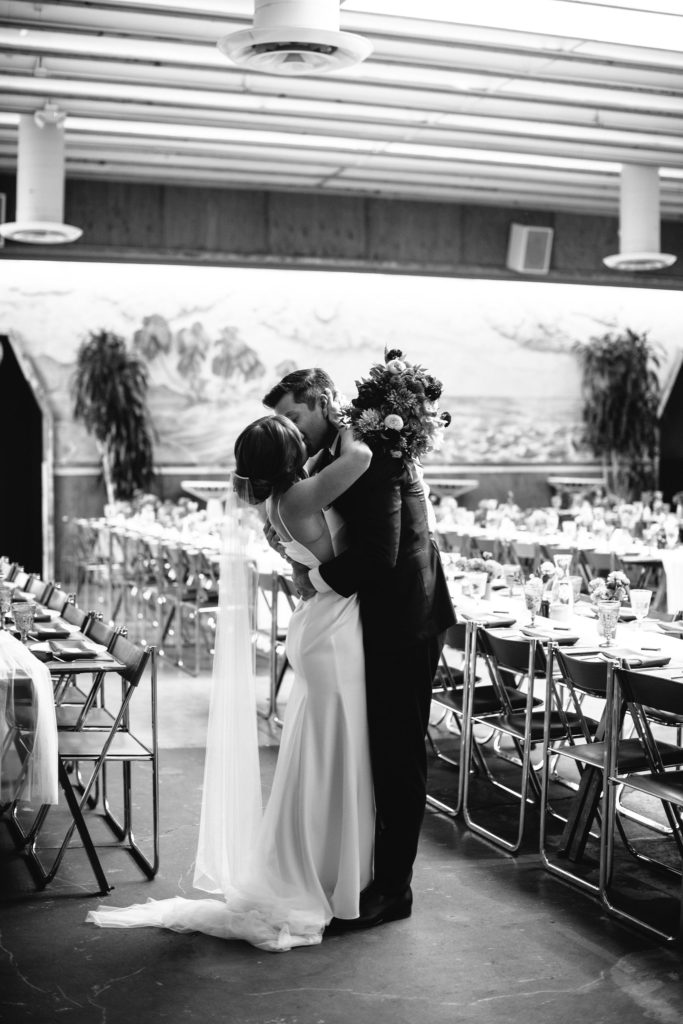 bride and groom kiss in reception space after wedding ceremony