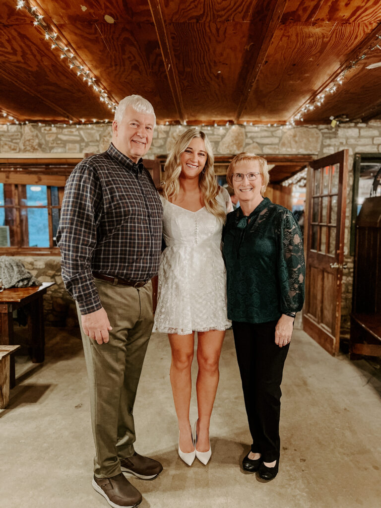 Kari of Feathered Arrow Events with parents during intimate wedding rehearsal in Texas while wearing mothers wedding dress