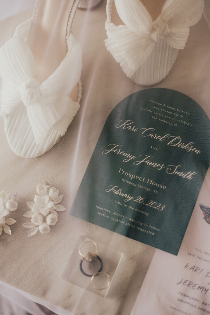 wedding detail shot with white bow heeled sandals and modern green wedding invitation suite 