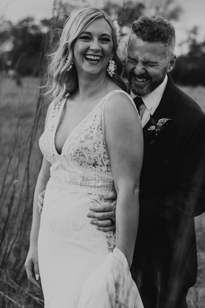 bride in deep v neck lace wedding dress with groom in navy blue suit